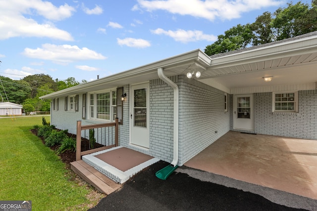 property entrance with a yard and brick siding