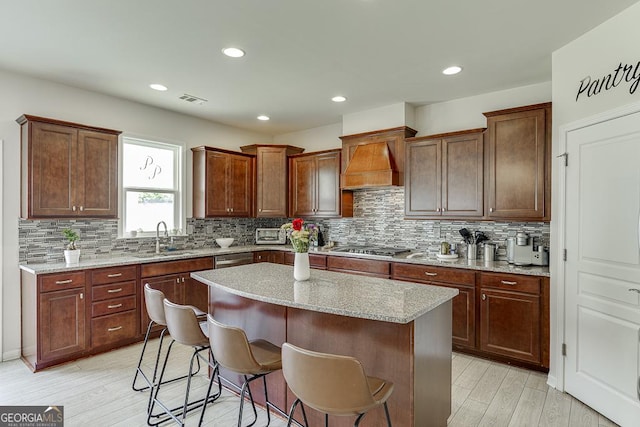 6438 Hickory Branch Dr, Hoschton, GA 30548 - kitchen with custom exhaust hood, a kitchen island, tasteful backsplash, a kitchen bar, and light wood-style flooring