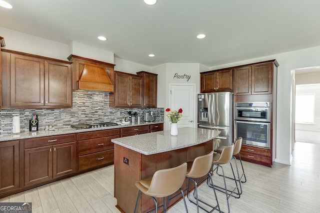 6438 Hickory Branch Dr, Hoschton, GA 30548 - kitchen featuring appliances with stainless steel finishes, a kitchen island, decorative backsplash, light wood-style flooring, and recessed lighting