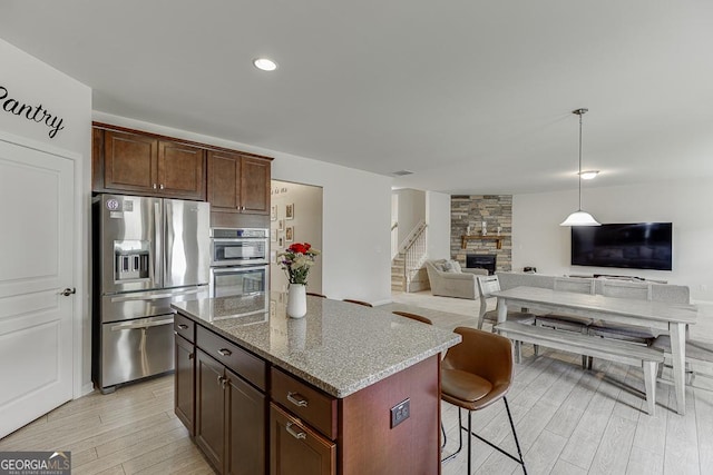 6438 Hickory Branch Dr, Hoschton, GA 30548 - kitchen with appliances with stainless steel finishes, a kitchen island, light wood finished floors, light stone countertops, and open floor plan