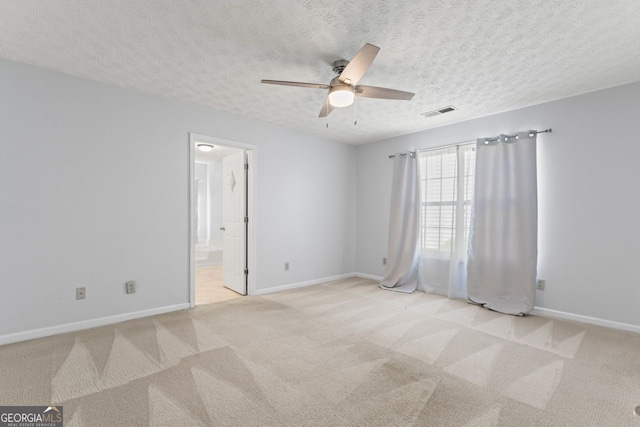 spare room featuring light colored carpet, baseboards, a ceiling fan, and visible vents
