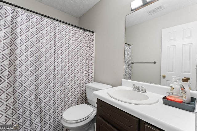 bathroom with toilet, visible vents, vanity, and a textured ceiling