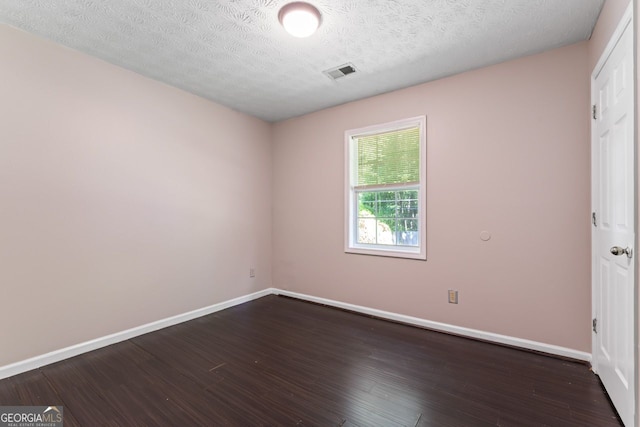 spare room with dark wood finished floors, visible vents, baseboards, and a textured ceiling