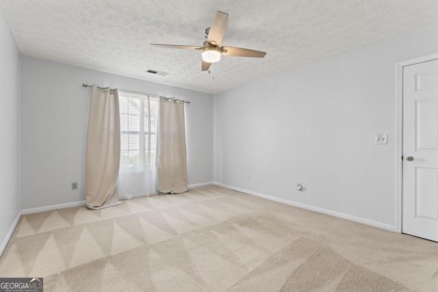 spare room with a ceiling fan, baseboards, visible vents, and light colored carpet