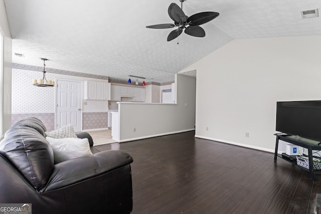 living room with a ceiling fan, wallpapered walls, visible vents, vaulted ceiling, and dark wood-style floors