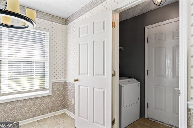 clothes washing area featuring washer / clothes dryer, a textured ceiling, light tile patterned floors, baseboards, and wallpapered walls