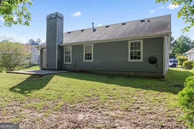 rear view of house featuring a patio area, a chimney, and a lawn