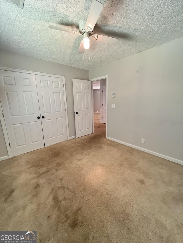 unfurnished bedroom with a closet, a textured ceiling, carpet, ceiling fan, and baseboards