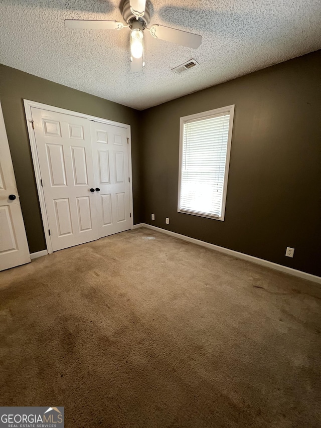 unfurnished bedroom featuring a textured ceiling, carpet flooring, and baseboards