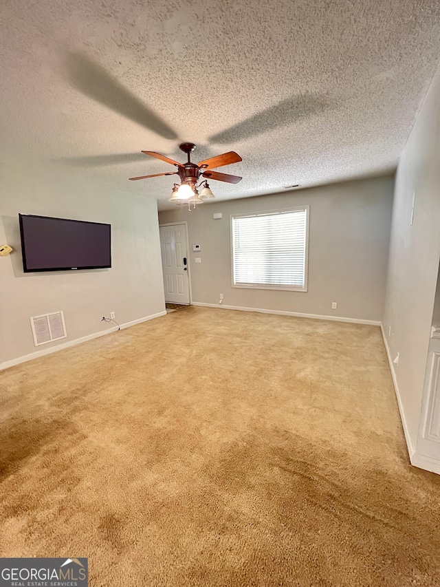 unfurnished living room with a textured ceiling, visible vents, light carpet, a ceiling fan, and baseboards