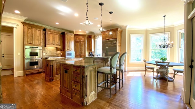 1345 Cashiers Way, Roswell, GA 30075 - kitchen featuring a kitchen island with sink, brown cabinets, built in appliances, a chandelier, and a breakfast bar area