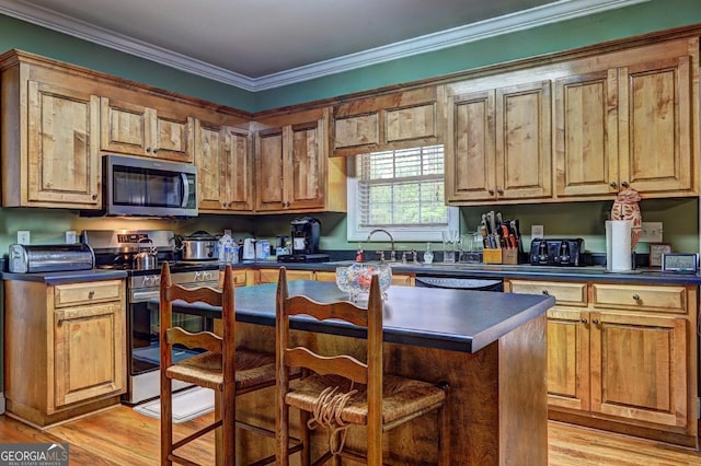 kitchen with ornamental molding, dark countertops, stainless steel appliances, and light wood-style floors