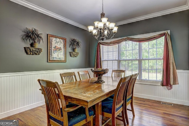 dining space featuring a chandelier, a wainscoted wall, visible vents, and wood finished floors