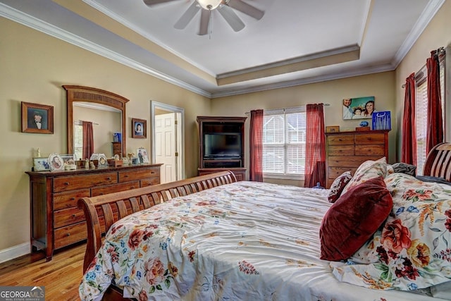 bedroom with baseboards, ceiling fan, crown molding, wood finished floors, and a raised ceiling