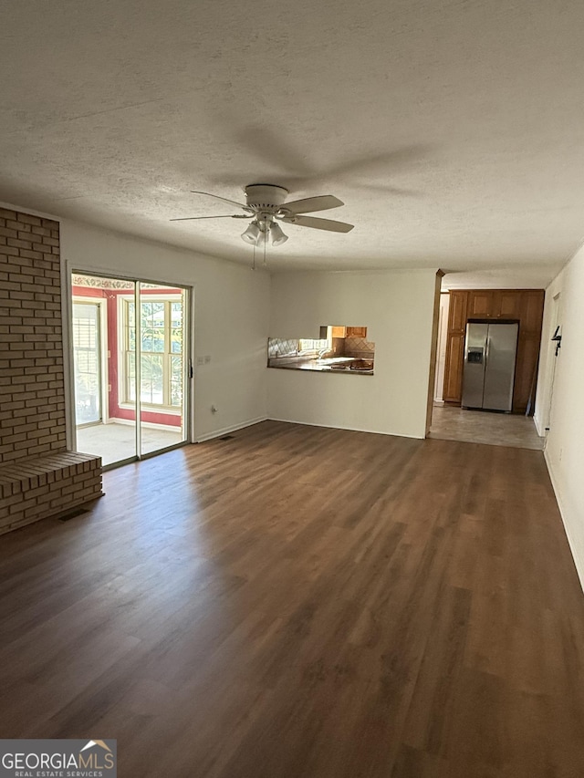 unfurnished living room featuring a textured ceiling, dark wood-type flooring, and a ceiling fan