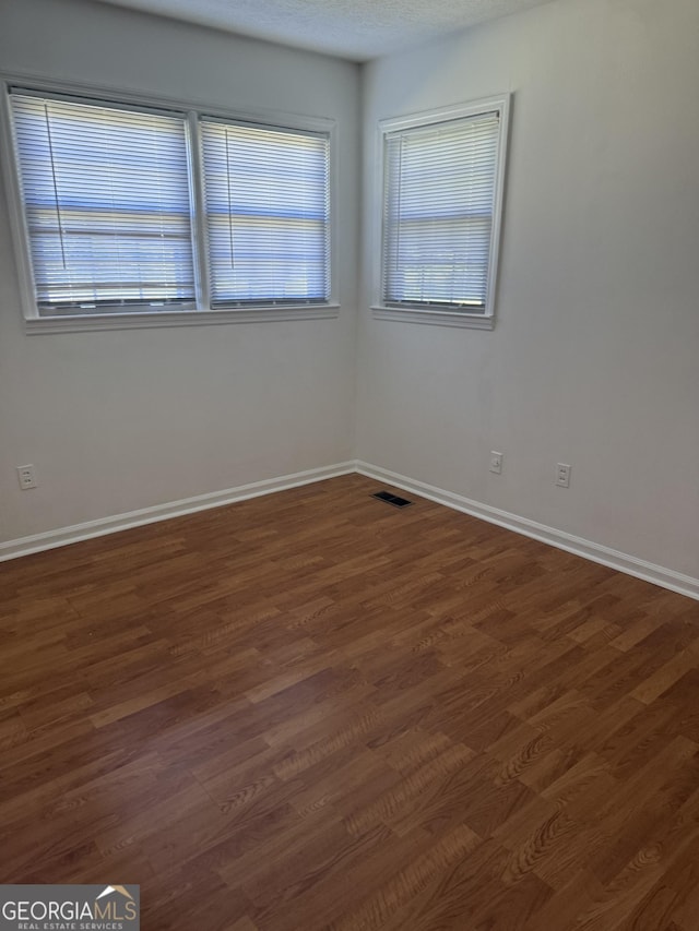 empty room featuring plenty of natural light, baseboards, and visible vents