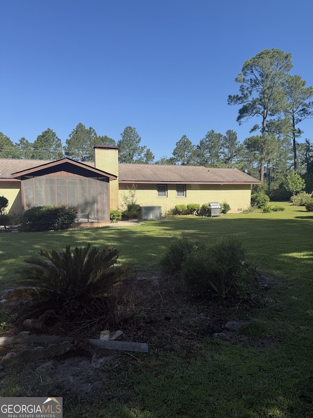 view of side of home featuring a sunroom and a lawn