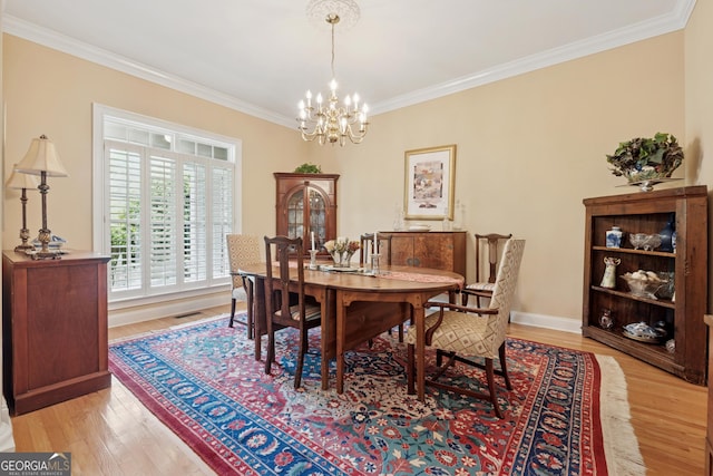 6125 Fouts Mill Rd, Douglasville, GA 30135 - dining area with light wood finished floors, crown molding, a chandelier, and baseboards