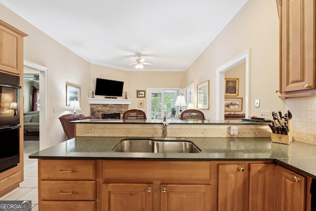 6125 Fouts Mill Rd, Douglasville, GA 30135 - kitchen featuring a sink, dark stone counters, a fireplace, crown molding, and a ceiling fan