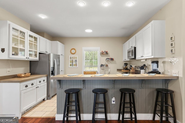 1261 Otter Slide Loop NE, Townsend, GA 31331 - kitchen featuring stainless steel appliances, glass insert cabinets, white cabinets, a peninsula, and recessed lighting