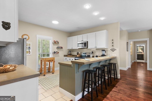 1261 Otter Slide Loop NE, Townsend, GA 31331 - kitchen with appliances with stainless steel finishes, a breakfast bar, white cabinets, baseboards, and recessed lighting