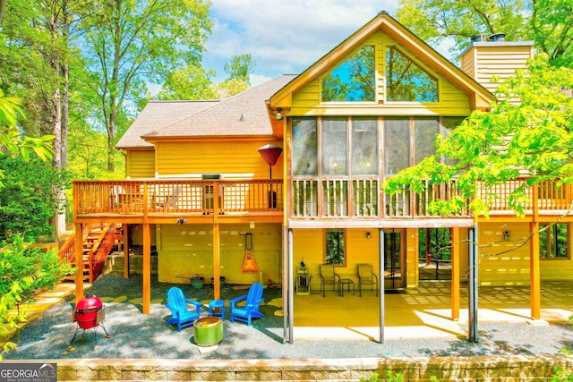 view of play area with stairway, a sunroom, a patio area, and a wooden deck