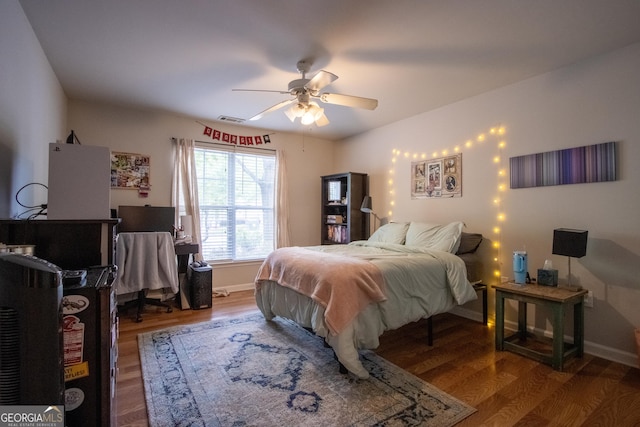 bedroom with baseboards, ceiling fan, visible vents, and wood finished floors