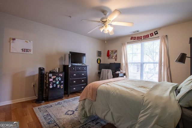 bedroom featuring ceiling fan, baseboards, visible vents, and wood finished floors