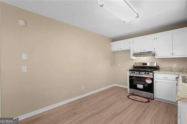 196 Highland Dr, Calhoun, GA 30701 - kitchen with under cabinet range hood, stainless steel gas range oven, white cabinetry, and light wood-style flooring