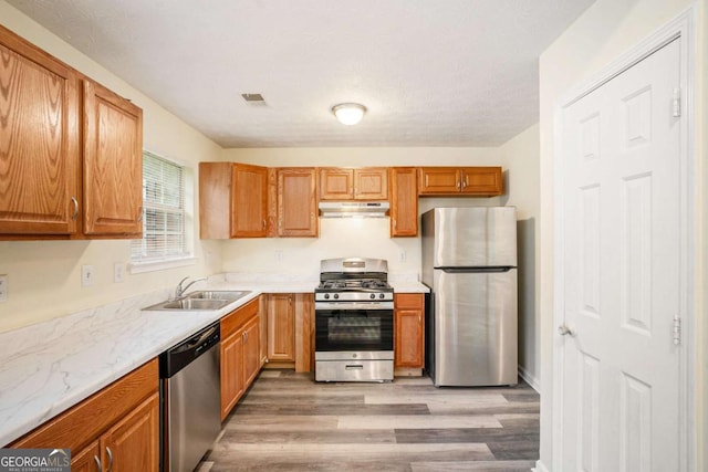 2722 S Hills, Riverdale, GA 30296 - kitchen with under cabinet range hood, a sink, brown cabinets, stainless steel appliances, and light wood-type flooring