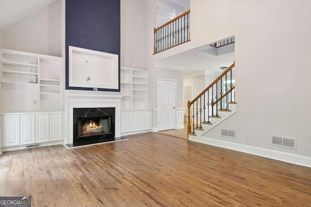unfurnished living room with visible vents, wood finished floors, and high vaulted ceiling