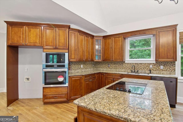 kitchen featuring a sink, brown cabinetry, light wood-style flooring, and appliances with stainless steel finishes