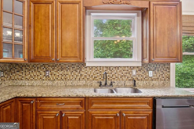 kitchen with decorative backsplash, stainless steel dishwasher, light stone countertops, and a sink