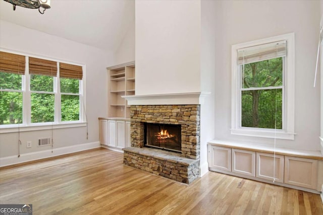 unfurnished living room featuring baseboards, a wealth of natural light, light wood-style floors, and a fireplace