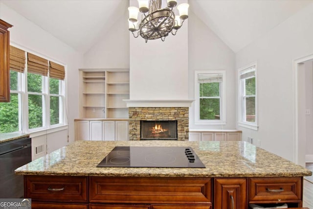 kitchen with black appliances, light stone counters, visible vents, an inviting chandelier, and a kitchen island