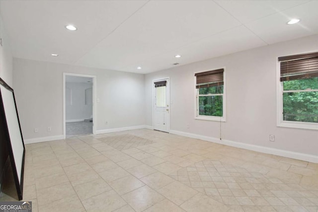 spare room featuring baseboards, a healthy amount of sunlight, and recessed lighting