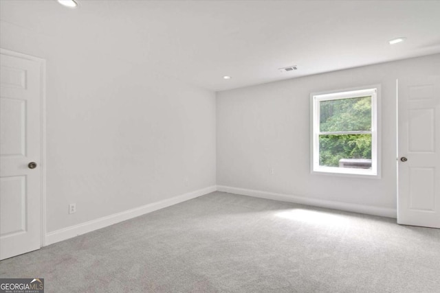 carpeted spare room featuring baseboards, visible vents, and recessed lighting