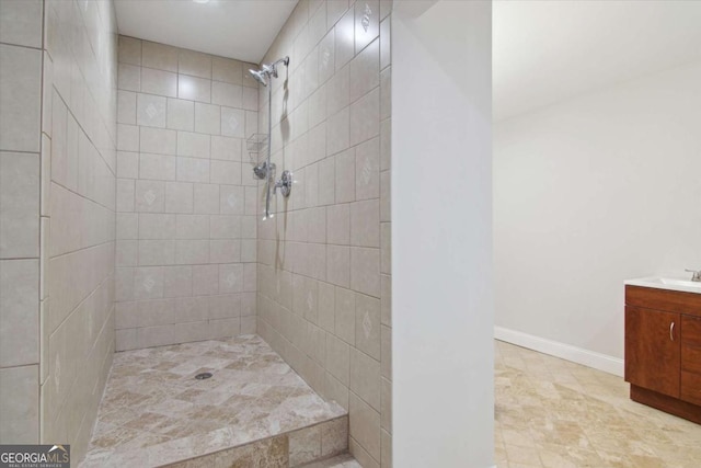 full bathroom with vanity, baseboards, and tiled shower