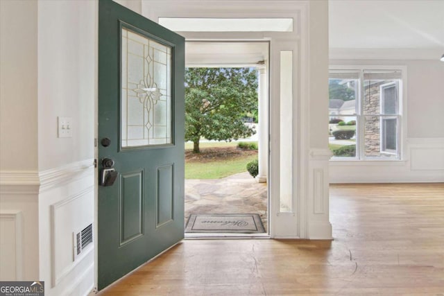 entryway with a decorative wall, visible vents, a wainscoted wall, and wood finished floors