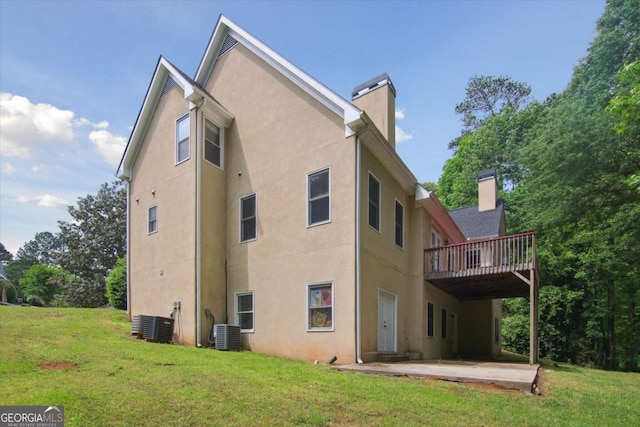 rear view of house featuring a patio area, a yard, stucco siding, a wooden deck, and a chimney