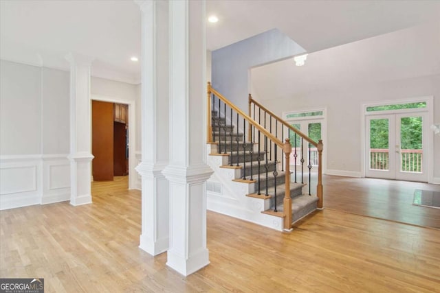 staircase with french doors, recessed lighting, decorative columns, and wood finished floors