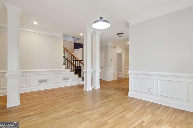 interior space with a decorative wall, a wainscoted wall, stairway, crown molding, and light wood-style floors