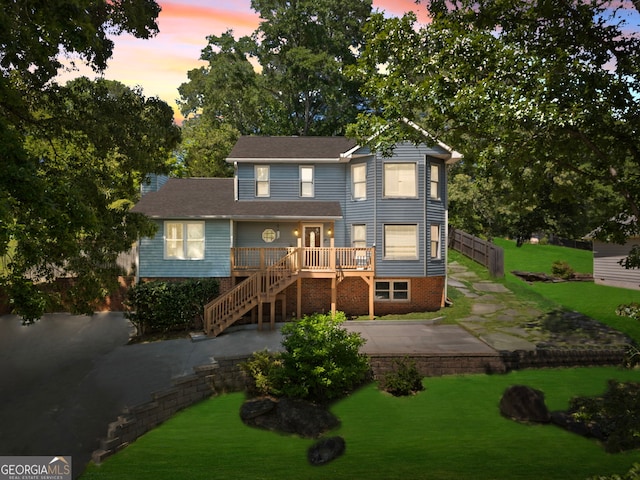 rear view of property featuring stairs, a lawn, a wooden deck, and a patio area