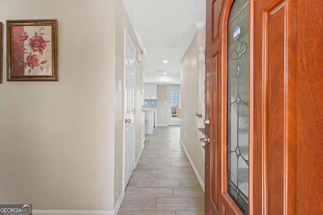 hallway featuring baseboards, a textured ceiling, wood finish floors, and recessed lighting