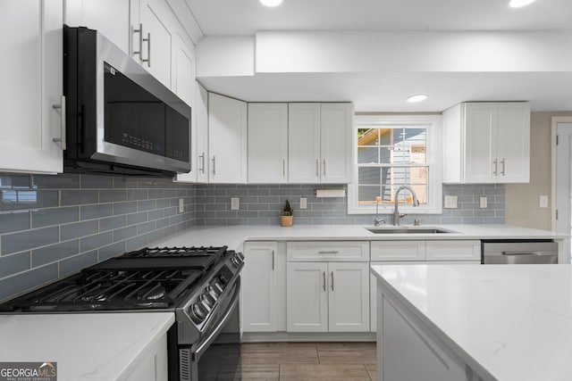 kitchen with stainless steel appliances, a sink, white cabinets, tasteful backsplash, and recessed lighting