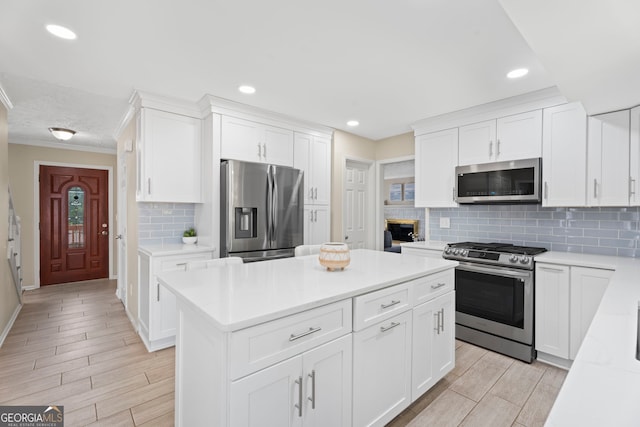 kitchen featuring appliances with stainless steel finishes, crown molding, tasteful backsplash, light countertops, and a kitchen island