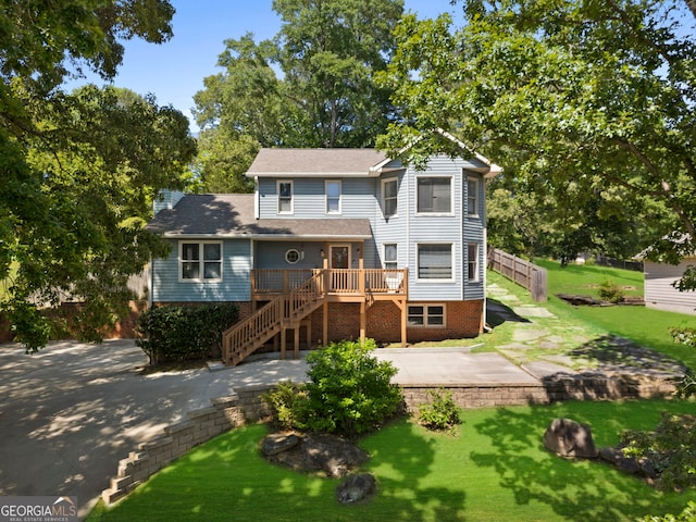 view of front of property featuring stairway, a wooden deck, a front lawn, and a patio