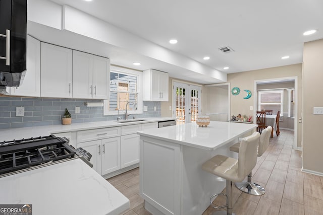 kitchen with a sink, a kitchen island, tasteful backsplash, french doors, and a kitchen breakfast bar