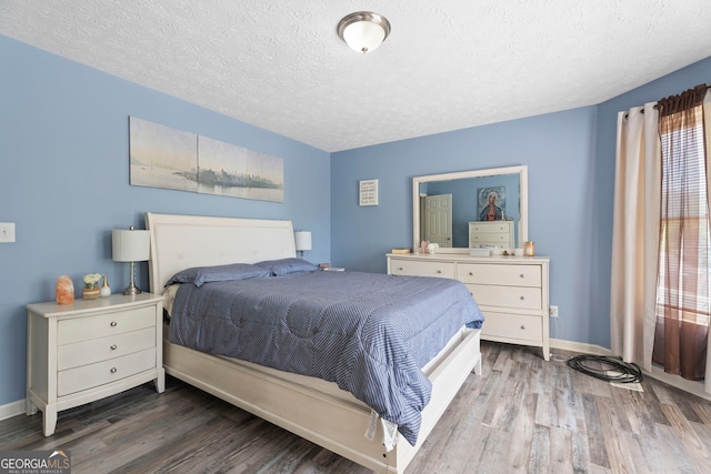 bedroom with a textured ceiling, wood finished floors, and baseboards