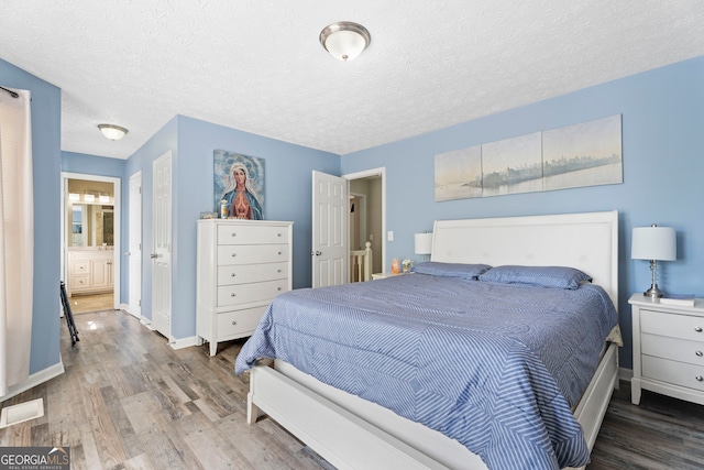 bedroom featuring wood finished floors, baseboards, and a textured ceiling